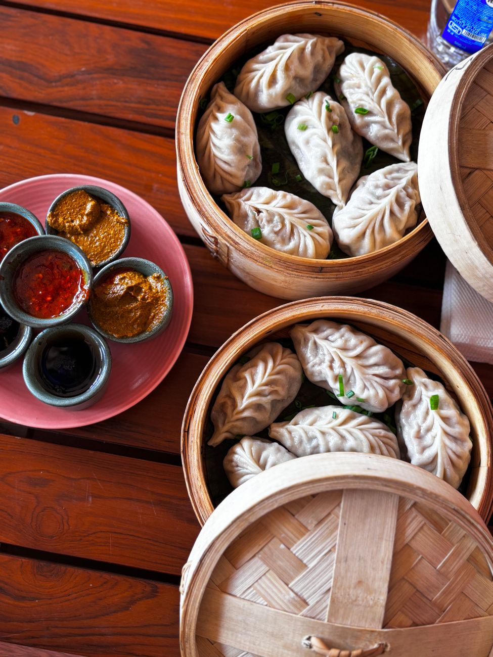 Steamed Nepali momos served in bamboo baskets with traditional dipping sauces