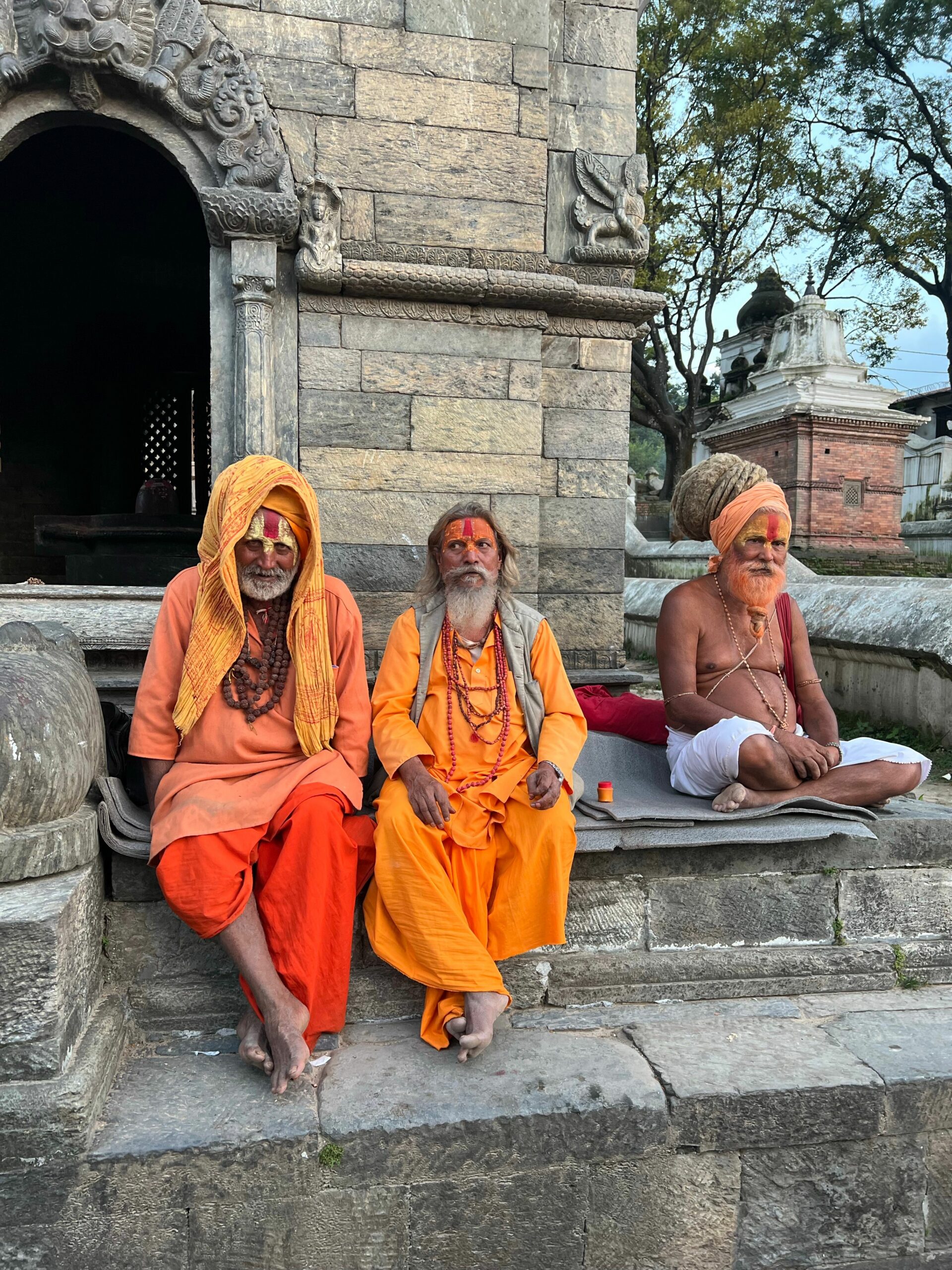 Three Hindu sadhus in traditional orange robes at Pashupatinath Temple in Kathmandu, Nepal