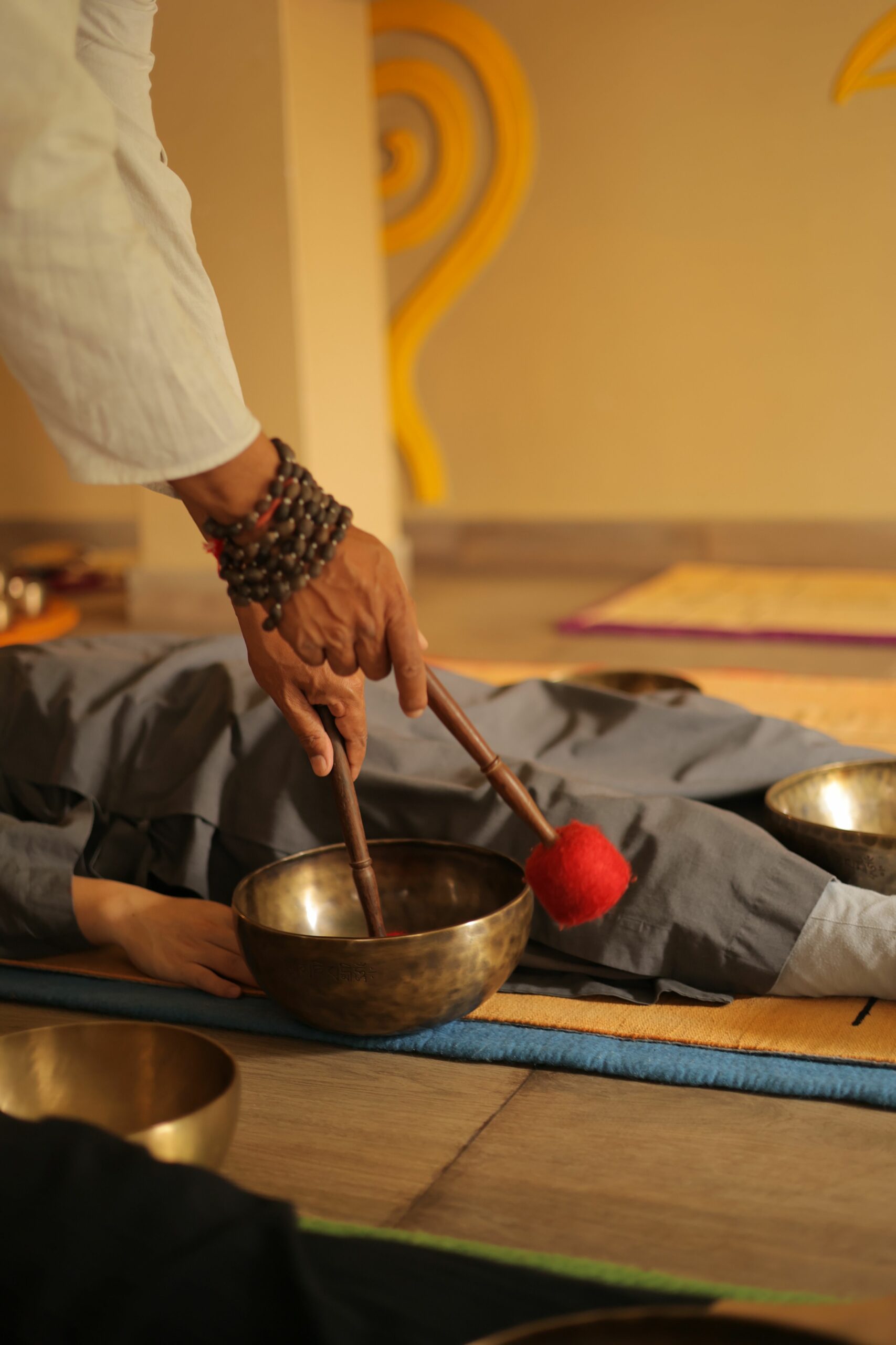 Singing bowl sound healing session with a practitioner using a wooden mallet in Nepal